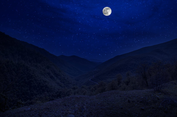 月圆之夜，山路穿过森林。风景优美的夜景乡村小路，夜晚有大月亮。长快门的照片图片下载
