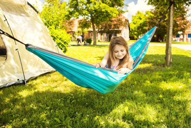 小白人女孩躺在吊床上，后面是帐篷图片下载