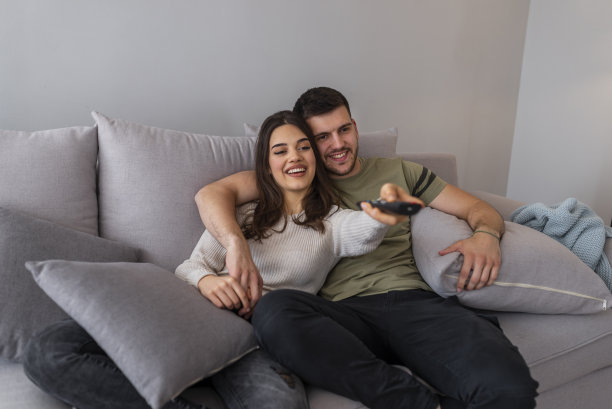 年轻夫妇晚上在家看电视。图片下载