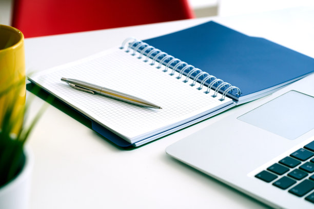 特写的白色桌面与笔记本电脑，咖啡杯，记事本，钢笔，计算器和其他项目。图片下载