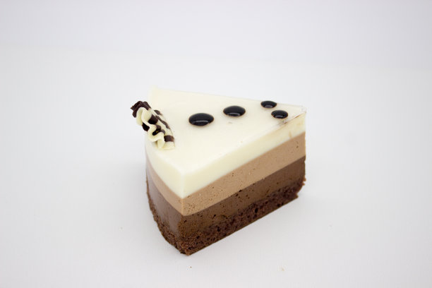 巧克力蛋糕。一块有黑巧克力、牛奶巧克力和白巧克力的蛋糕。在白色的背景上图片下载