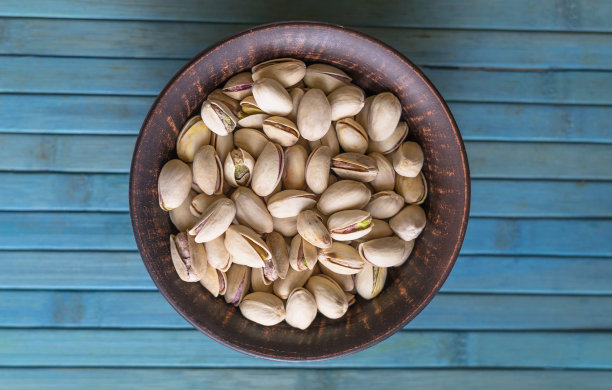 健康的食物背景图片近距离开心果。纹理上的白色灰色表顶视图。果仁，开心果，放在盘子里图片下载