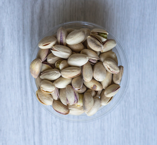 健康的食物背景图片近距离开心果。纹理上的白色灰色表顶视图。果仁，开心果，放在盘子里图片下载