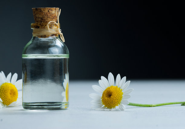 甘菊精油在玻璃瓶中与新鲜的甘菊花，芳香的雏菊油，美容治疗。水疗中心的概念图片下载