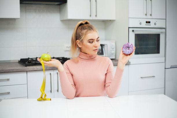 节食的概念。年轻女子在水果和糖果之间选择图片下载