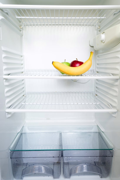 鲜红色和绿色的苹果和香蕉在打开的空冰箱的架子上。减肥饮食概念。图片下载