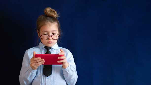 手持智能手机的聪明学龄前女孩图片下载