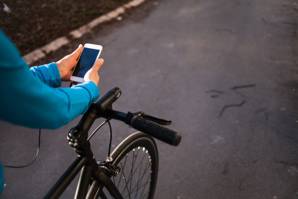 资深女运动员在自行车上使用智能手机图片下载