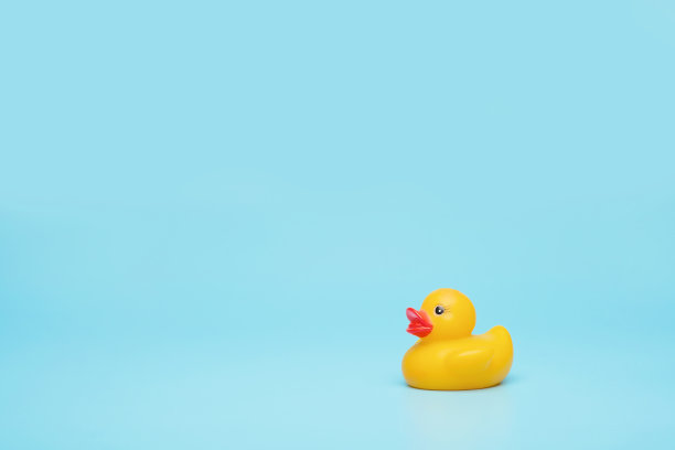 黄色橡胶玩具水鸟在一个蓝色的背景。节省你的空间，游泳池的概念。图片下载