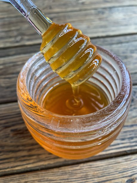 蜂箱形状的蜂蜜容器与液体蜂蜜靠近图片下载
