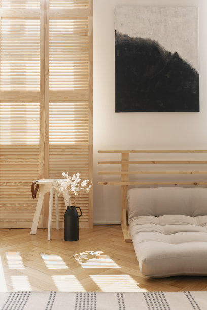 现代卧室室内的木桌和黑色花瓶上的花，旁边是米色的蒲团床，实景图片下载