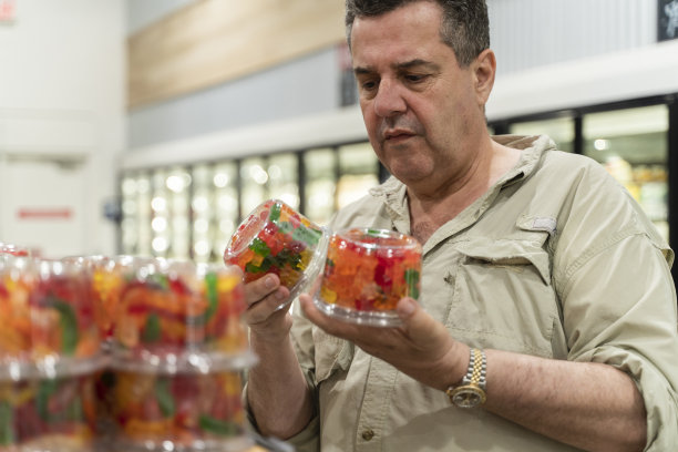 一位年长的拉丁裔男子在杂货店里选购糖果。图片下载