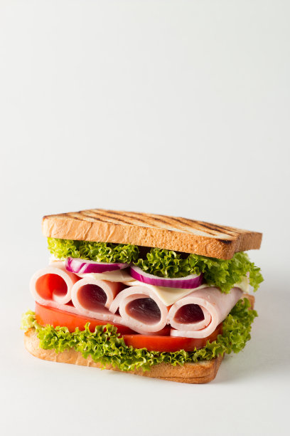 俱乐部三明治的特写照片。三明治与肉，火腿，意大利腊肠，沙拉，蔬菜，生菜，番茄，洋葱和芥末在新鲜的黑麦面包切片在木制背景。橄榄背景。图片下载