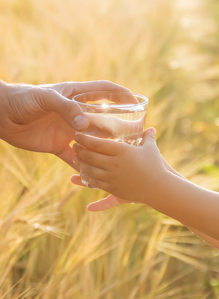 父亲给了孩子一杯水。有选择性的重点。图片下载