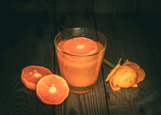 鲜榨桔子汁在一个杯子和新鲜桔子在木桌上。图片下载