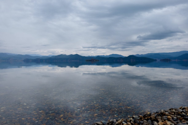 宽阔宁静纯净的湖。雾中的蓝山。白云覆盖着天空。图片下载