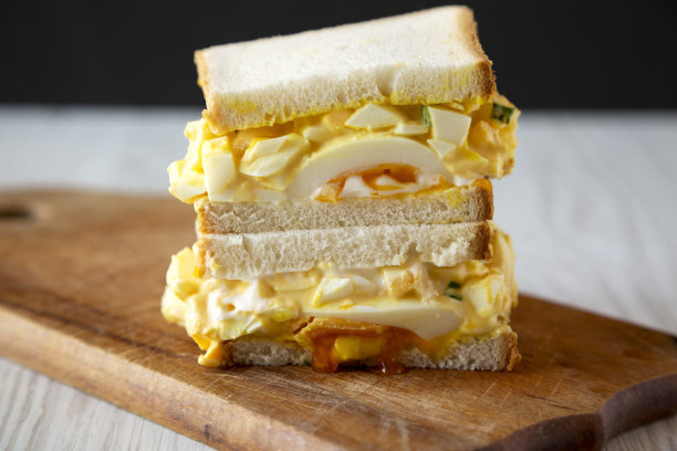 早餐自制的鸡蛋沙拉三明治放在质朴的木板上，侧视图。特写镜头。图片下载