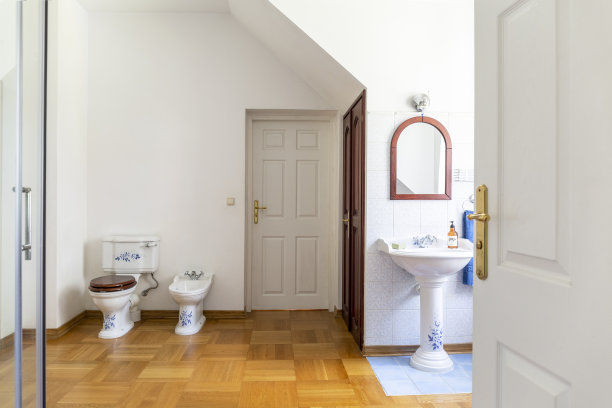 简单的浴室内部，镜子上方的刷面盆，厕所旁边的门。真实的照片图片下载