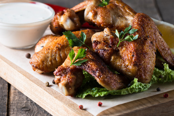 烧烤鸡翅与薯条和啤酒的特写照片。烤肉配酱汁，番茄酱，蛋黄酱。快餐和垃圾食品的概念。图片下载