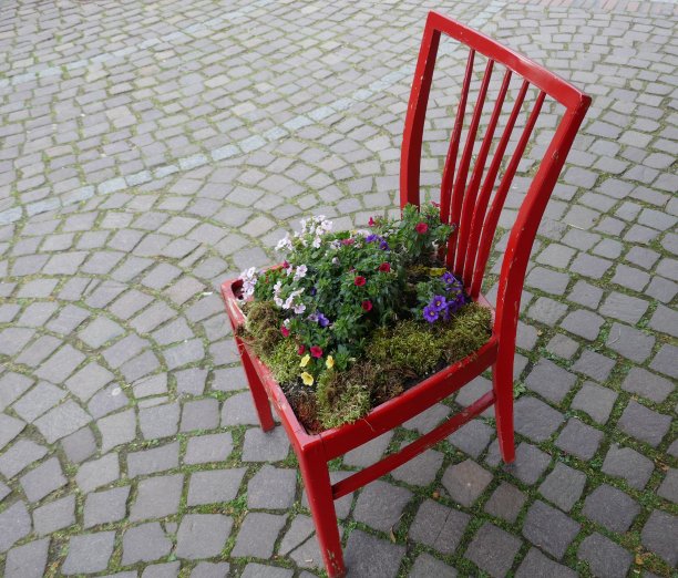 古老的红色木凳上，种着盛开的鲜花。装饰在花店前面的走道上图片下载