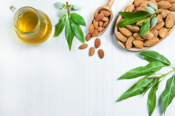 杏仁油和杏仁果仁装在木铲里，带壳杏仁装在竹碗里放在白色的桌子上，新鲜的杏仁放在杏仁树枝上图片下载