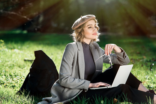 在户外工作的好处。教育技术和互联网概念。戴着时尚太阳镜的女孩坐在公园的草地上用笔记本电脑工作。自然环境的办公室。图片下载