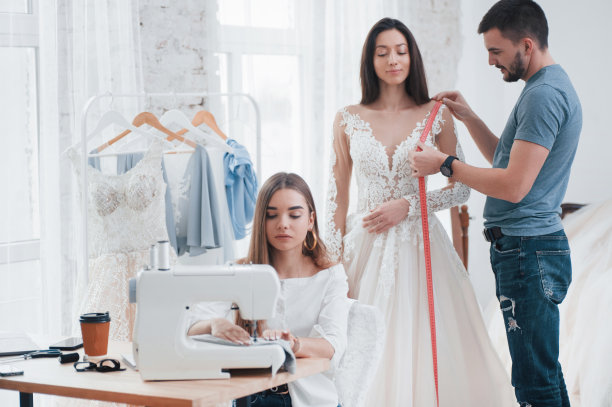 时尚和美丽的新娘。在手工缝制衣服的工作室里试穿衣服的过程图片下载
