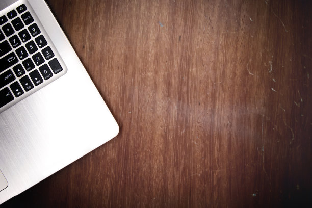 笔记本电脑放在旧的棕色木制办公桌旁，与复印空间垂下视野，工作空间的背景图片下载