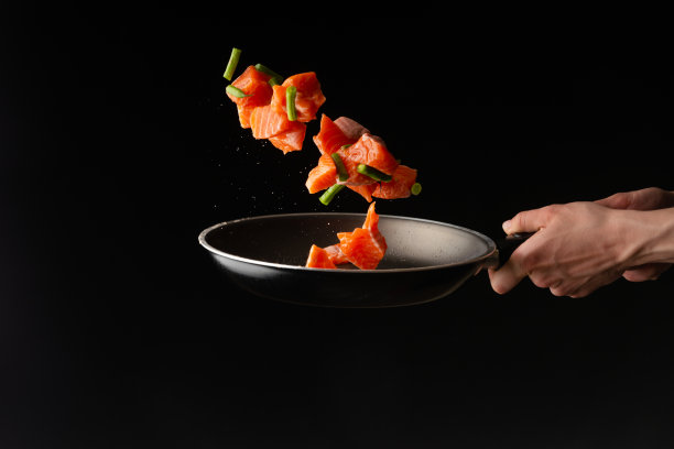 厨师在平底锅里用青豆烹制三文鱼或鳟鱼片，在黑色背景上制作设计、食谱、菜单、餐厅或酒店标志、烹饪、美食、横向照片图片下载