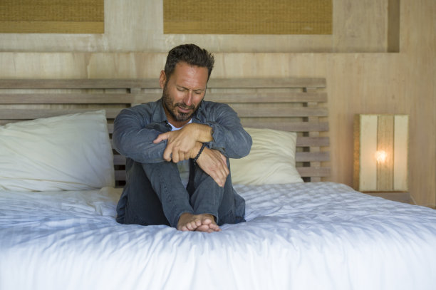 生活方式的家庭肖像年轻有吸引力的不知所措和沮丧的男人坐在床上哭泣，悲伤和沮丧遭受抑郁危机从工作或离婚问题胎儿姿势图片下载