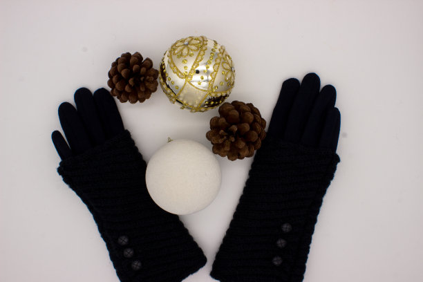 蓝色的手套，白色和金色的圣诞球和两个松果在白色的背景。新年和圣诞节的概念。图片下载