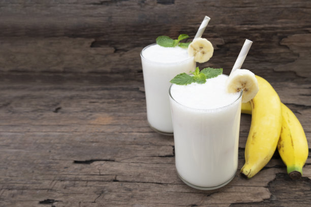 香蕉椰子新鲜鸡尾酒香草冰沙果汁和白香蕉水果饮料健康的味道美味的奶昔在玻璃杯上的木制背景。图片下载