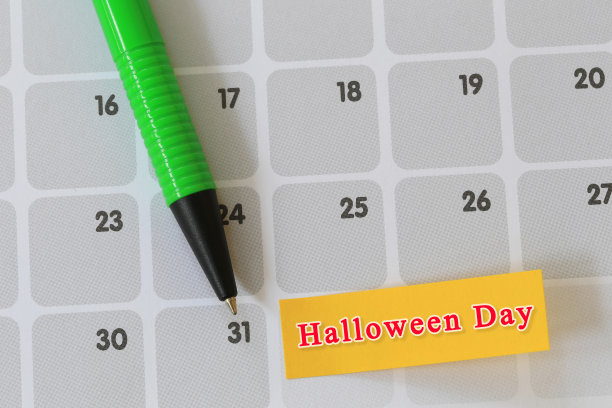 绿色的笔在日历纸上指向第31天，并有万圣节的文字。图片下载
