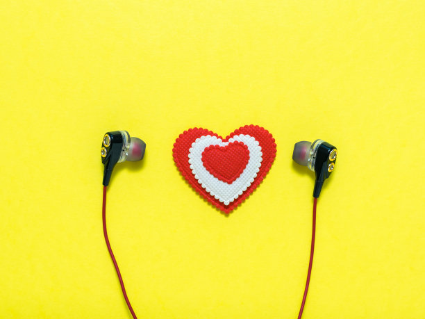 白色和红色的心耳机在黄色的背景。平的。图片下载
