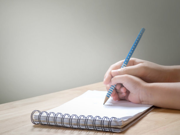 大人牵着孩子的手在笔记本上写字图片下载