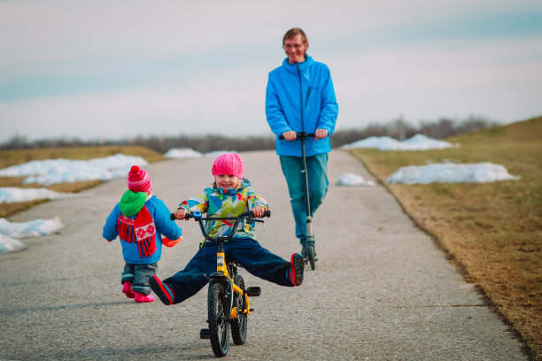 积极运动的家庭-父亲在学校和孩子在外面，小女孩在自行车上图片下载