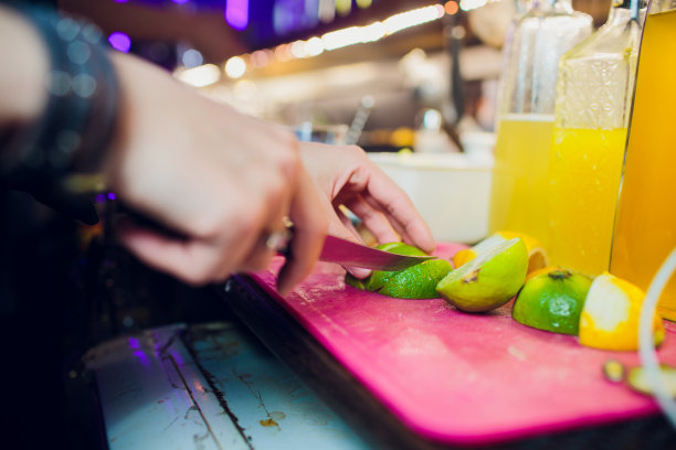 特写图片的调酒师的手切生，成熟和新鲜的绿色酸橙异国水果饮料准备组成。图片下载