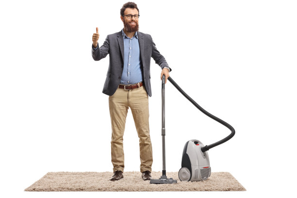 一个年轻人拿着吸尘器站在地毯上，竖起大拇指图片下载