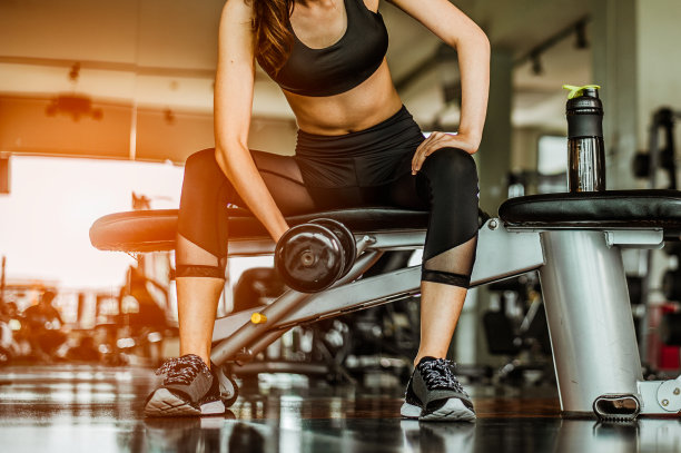 健美运动员在健身房用哑铃锻炼。健美运动员用哑铃锻炼。健身肌肉的身体图片下载