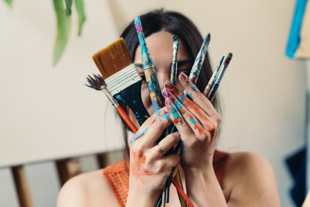 年轻的女艺术家，双手沾满了色彩图片下载