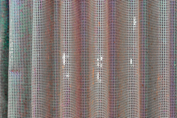 背景照片，弯曲的金属屏幕用作一个通气的旧农用设备。褪了色的绿色油漆，锈色的橙色。金属通风网孔。图片下载