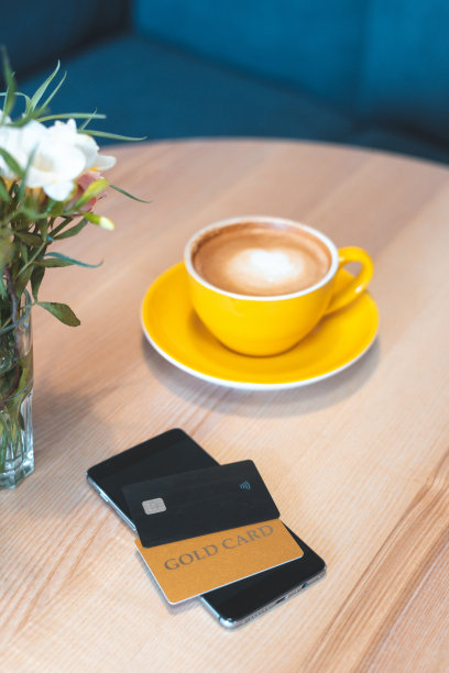 高角度俯视图或头顶，平躺和垂直照片的现代数字智能手机与两张信用卡躺在咖啡馆的木桌上，舒适和明亮的内部图片下载