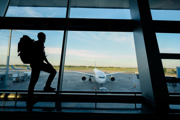 一个背着背包的年轻人靠近航站楼窗口图片下载