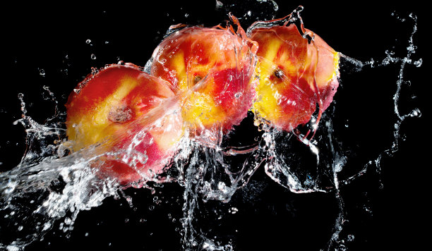 新鲜油桃在水溅在黑色的背景图片下载