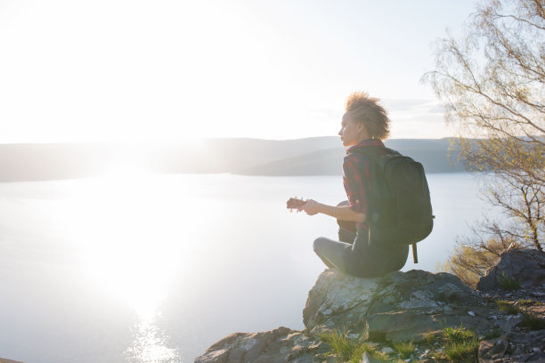 女人旅行者有一个包和吉他尤克里里享受海景度假。图片下载