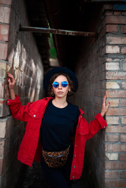 在一堵砖墙的背景上，那个穿着红夹克戴着太阳眼镜的女孩图片下载