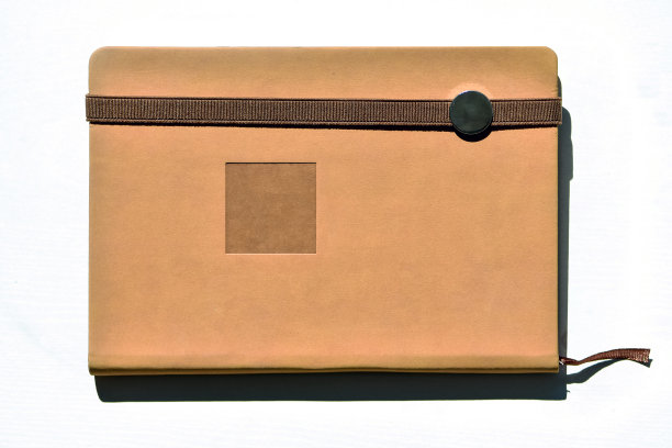 笔记本(米色、棕色)，放在一张白色的桌子上，被自然光照亮。图片下载