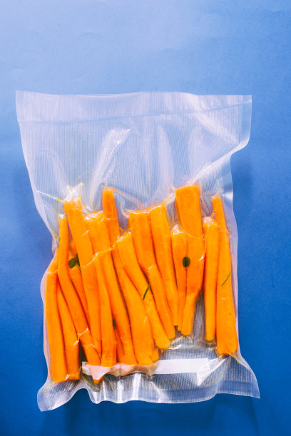 真空密封的蔬菜，胡萝卜，在一个蓝色的背景俯视图，准备用真空烹调机图片下载