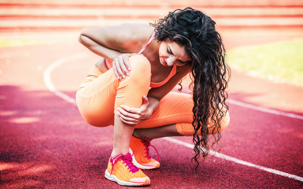 女运动员扶着她受伤的腿。运动,休闲的概念图片下载