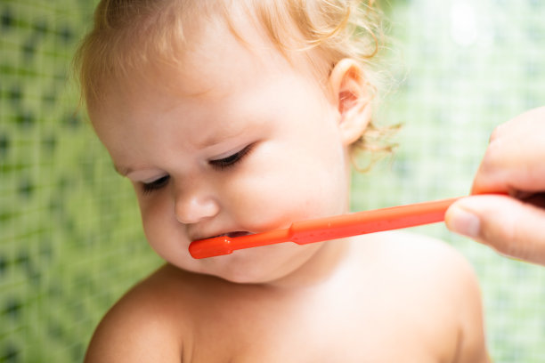 可爱的蹒跚学步的小女孩在浴室刷牙。可爱的婴儿坐在水槽里。爸爸帮孩子刷牙。特写图片下载